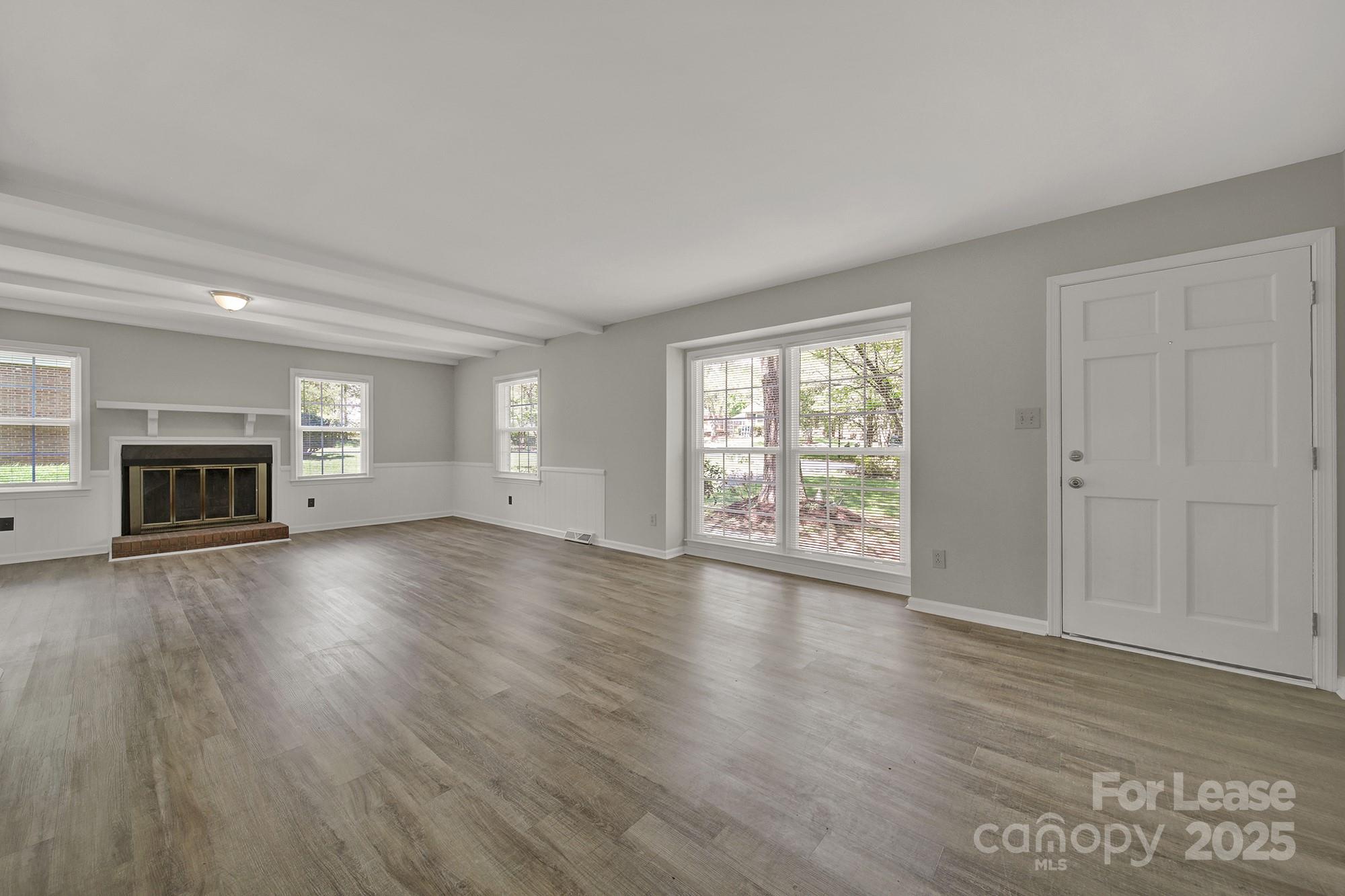 515 Wilcrest Drive Matthews, NC 28105 - Photo 3 of 19 an empty room with wooden floor fireplace and windows