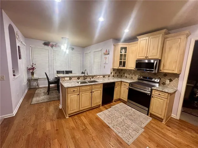 a kitchen with granite countertop kitchen island stainless steel appliances a stove refrigerator sink and cabinets