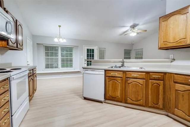 a kitchen with stainless steel appliances granite countertop a stove a sink dishwasher and white cabinets with wooden floor