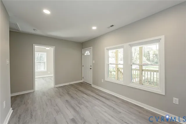 a view of an empty room with wooden floor and a window
