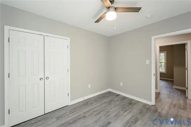 an empty room with wooden floor closet and windows