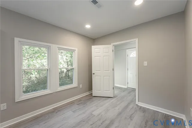 an empty room with wooden floor and windows