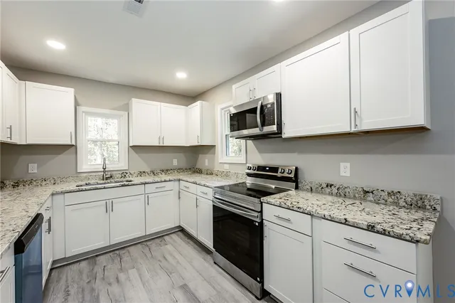 a kitchen with granite countertop a sink stainless steel appliances and cabinets