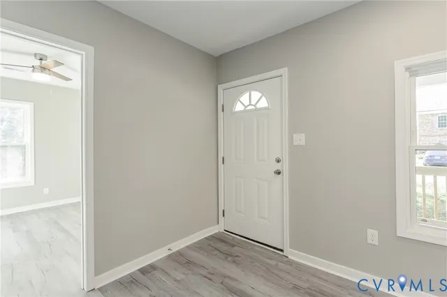an empty room with wooden floor mirror and windows