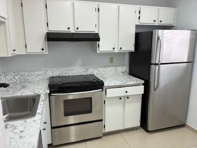 a kitchen with granite countertop white cabinets and white appliances