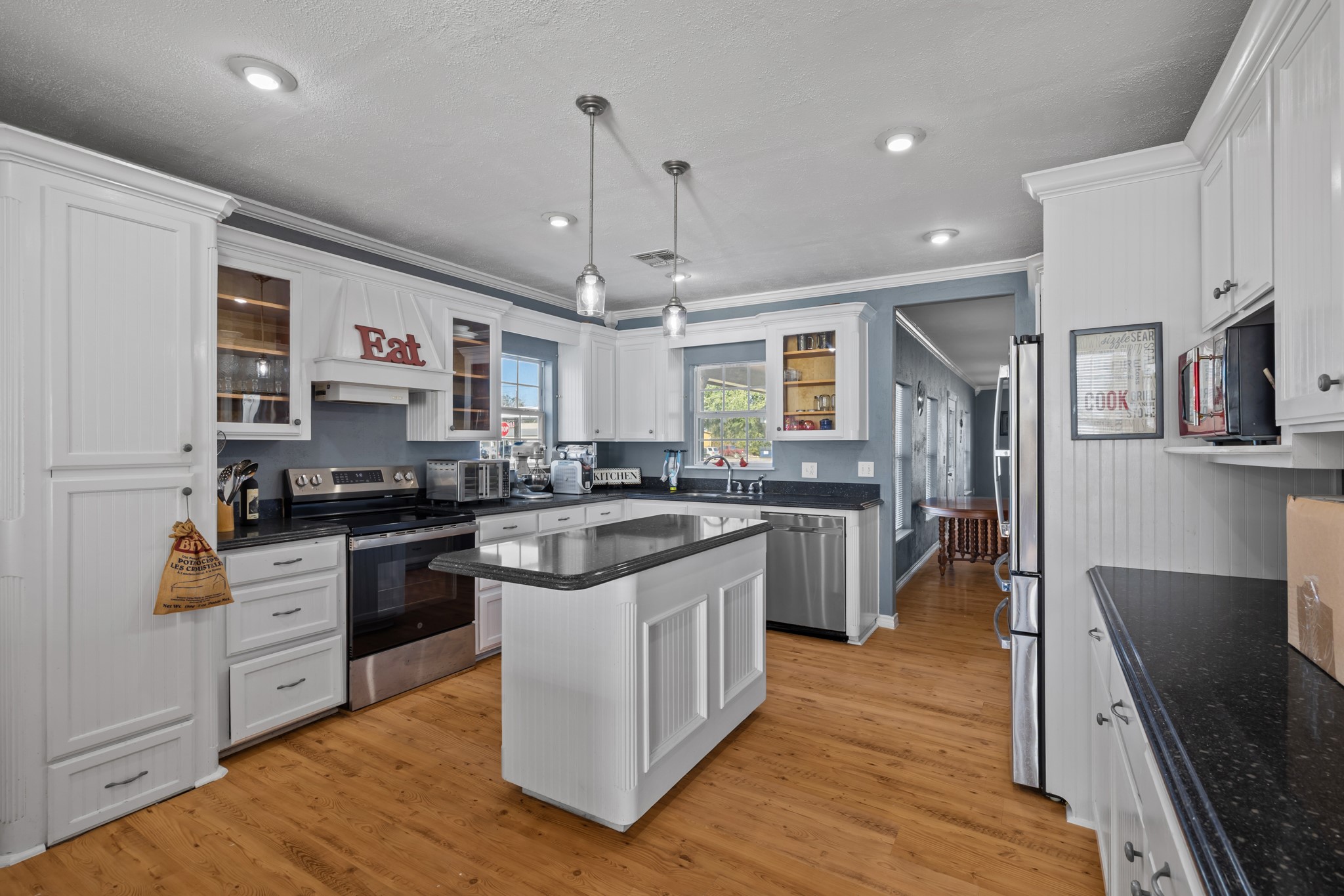 2006 Main Street Danbury, TX 77534 - Photo 13 of 30 a kitchen with stainless steel appliances granite countertop a stove top oven a sink dishwasher a refrigerator and white cabinets with wooden floor