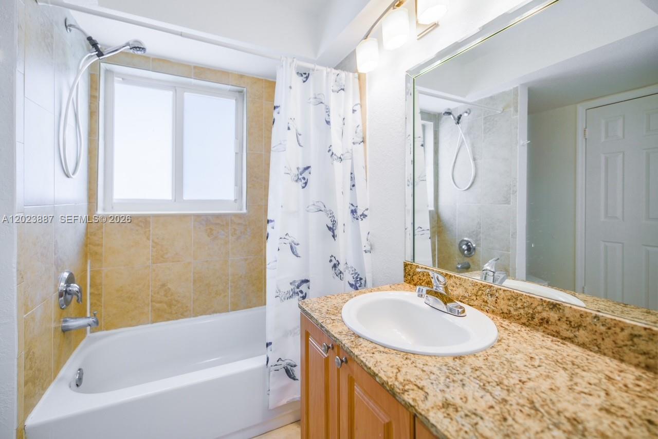7737 Southwest 88th Street, Unit C312 Miami, FL 33156 - Photo 23 of 32 a bathroom with a granite countertop sink a mirror a bathtub and shower