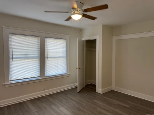 an empty room with wooden floor ceiling fan and windows
