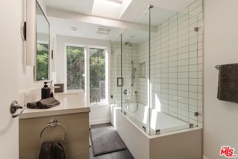 a bathroom with a tub a sink a mirror and next to a window