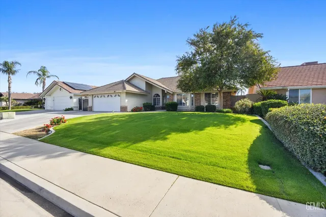 a view of a house with a big yard potted plants and large tree