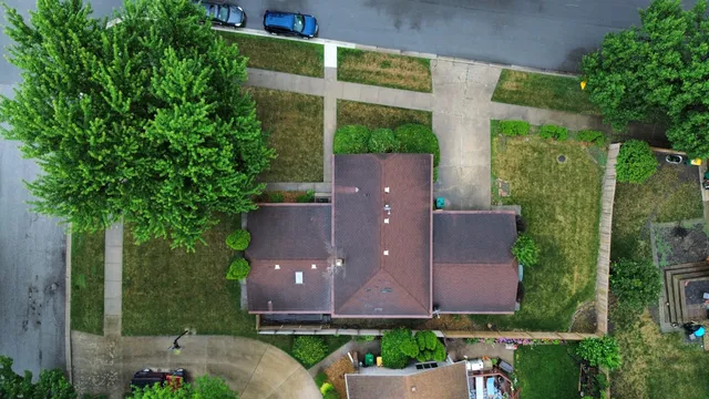 an aerial view of a house with a yard and a large tree