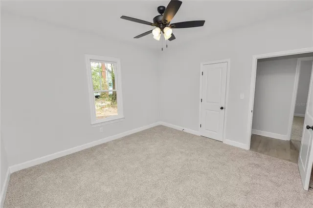 an empty room with windows and fan