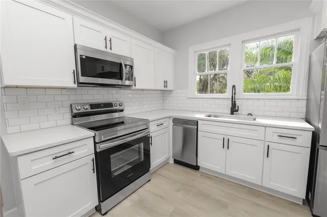 a kitchen with white cabinets appliances and a sink