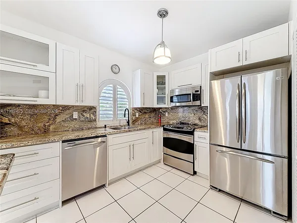 a kitchen with granite countertop white cabinets and white stainless steel appliances