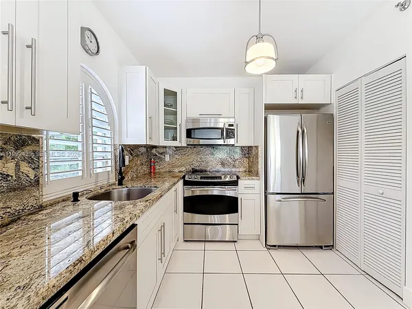 a kitchen with granite countertop a refrigerator oven a sink and cabinets