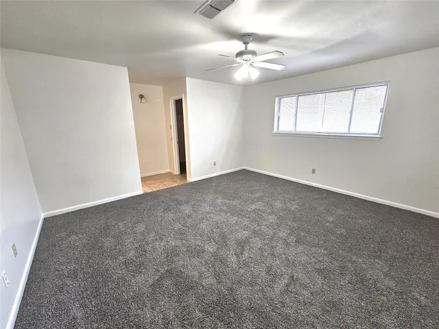 an empty room with a chandelier fan and windows