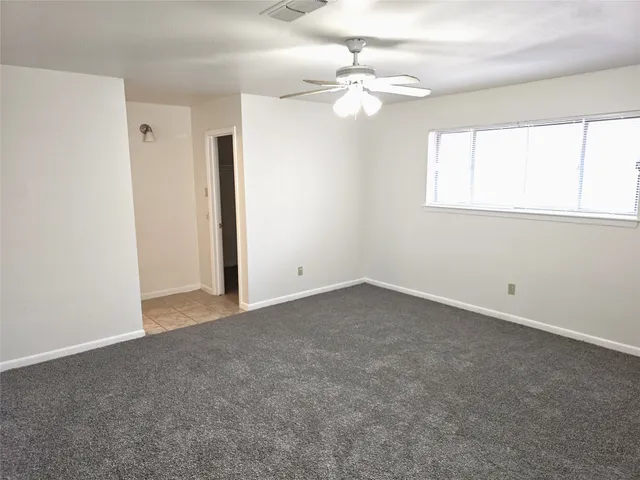 an empty room with a window and a fan