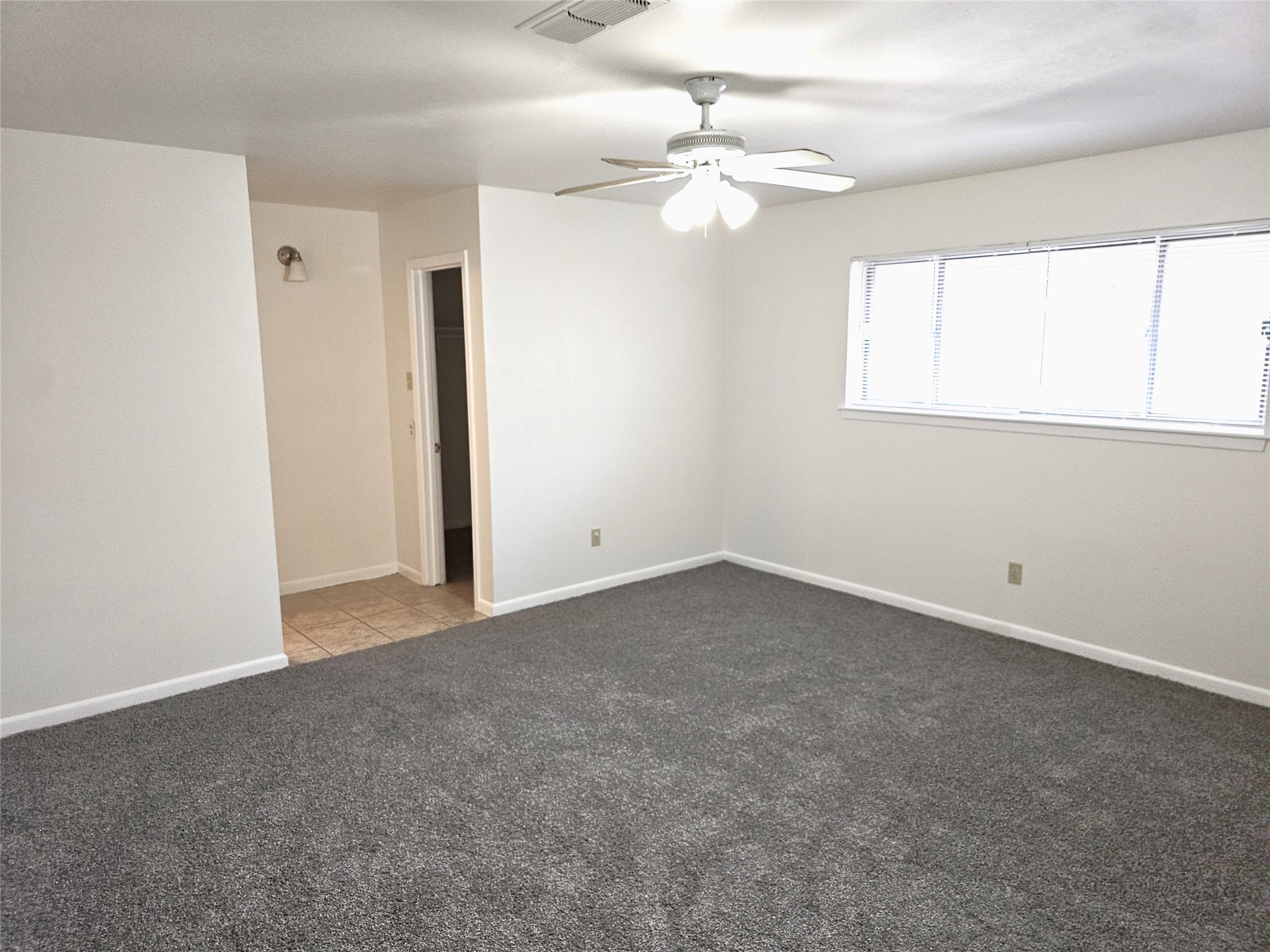 11427 Kirkmeadow Drive Houston, TX 77089 - Photo 15 of 24 an empty room with a chandelier fan and windows