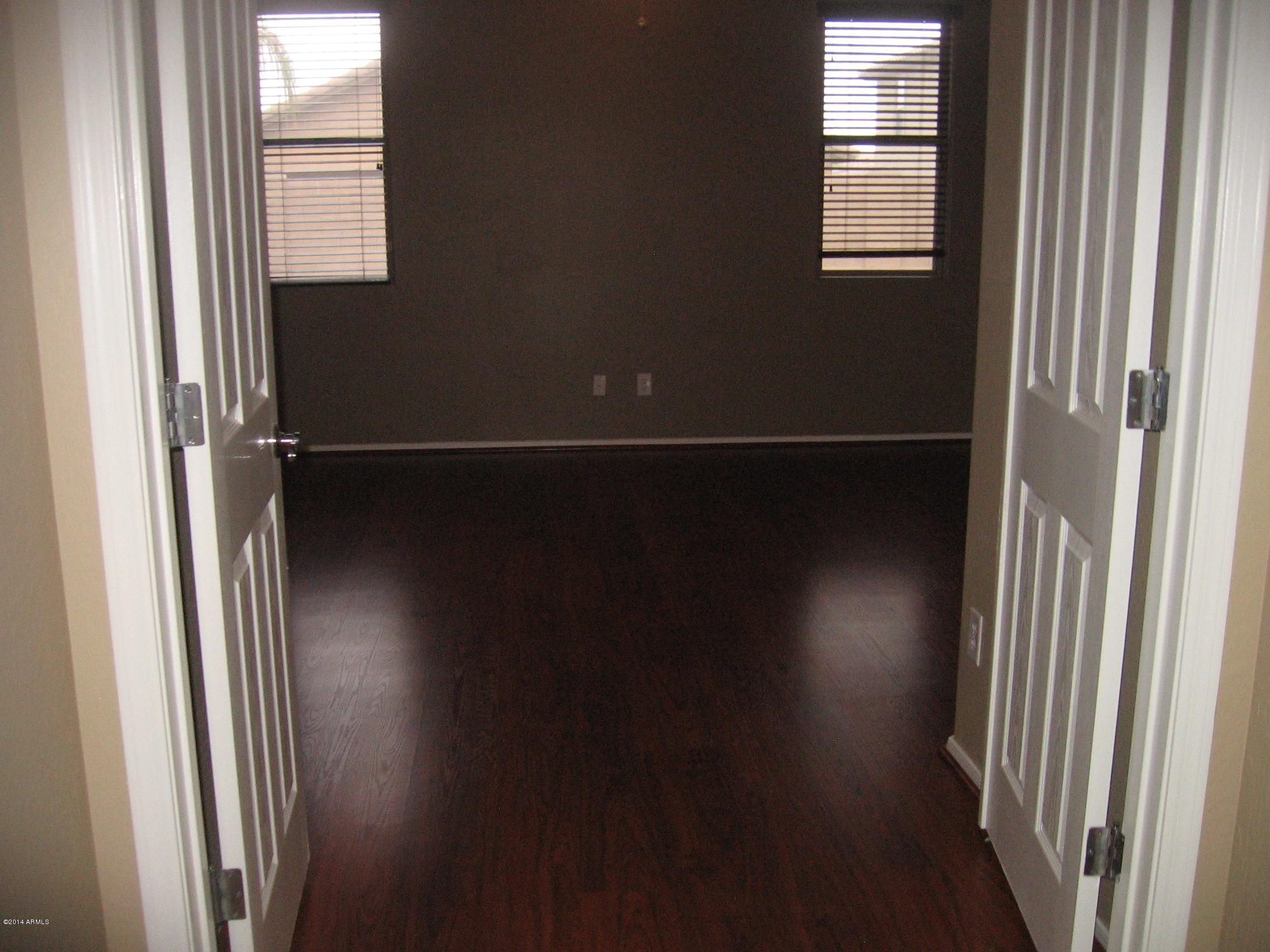 18022 West Hatcher Road Waddell, AZ 85355 - Photo 14 of 38 an empty room with wooden floor and windows