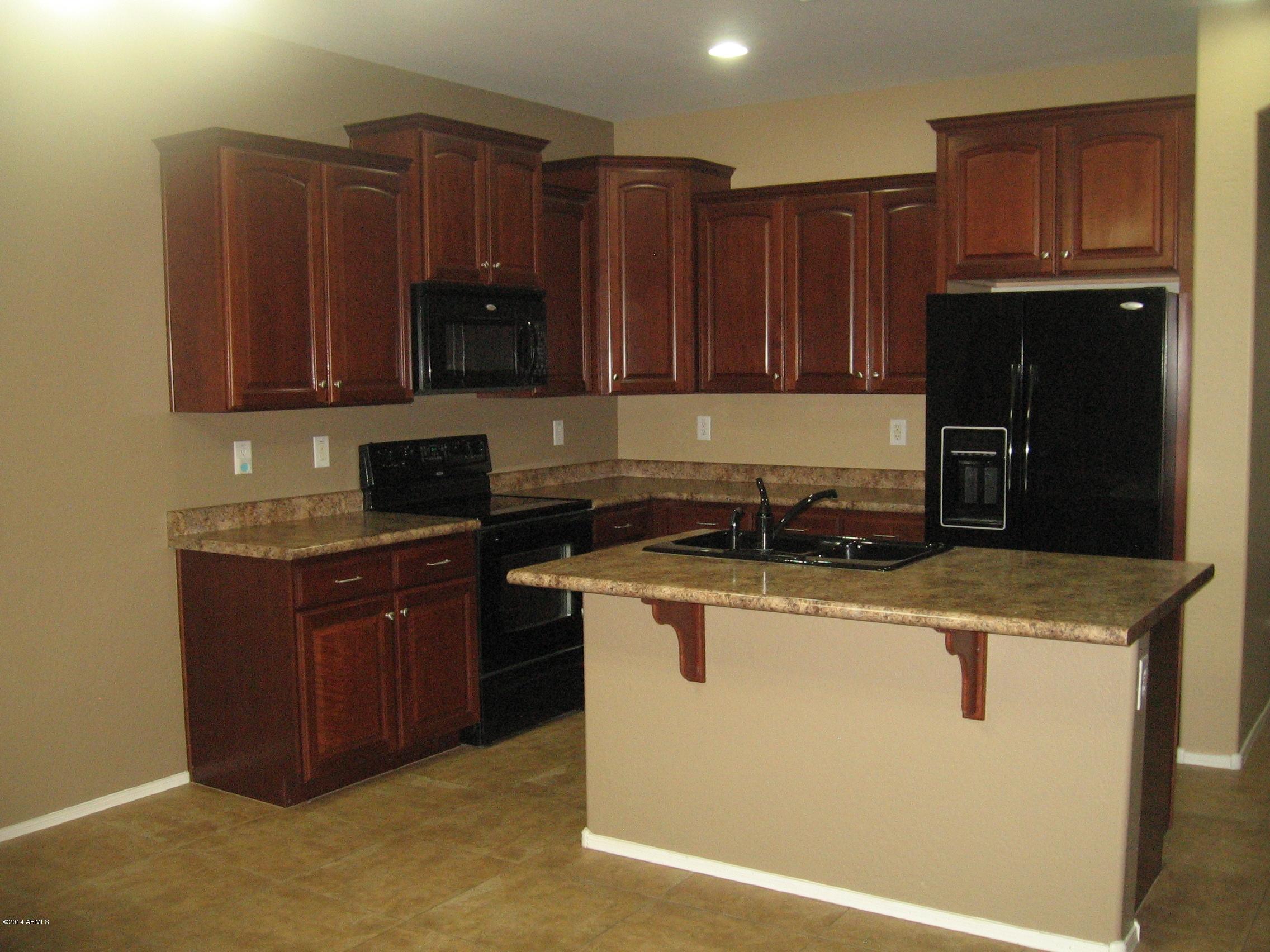 18022 West Hatcher Road Waddell, AZ 85355 - Photo 3 of 38 a kitchen with wooden cabinets and black appliances