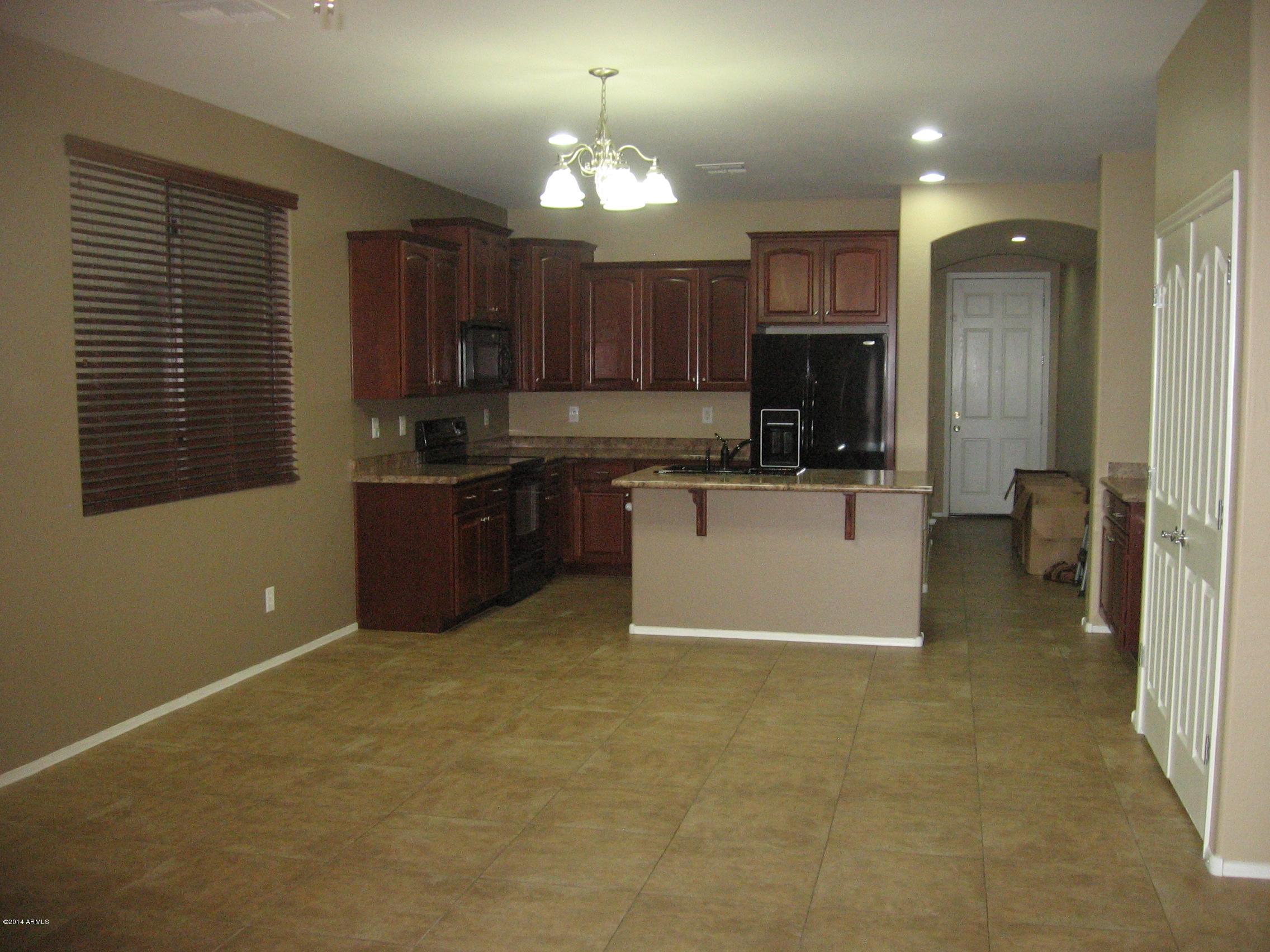 18022 West Hatcher Road Waddell, AZ 85355 - Photo 7 of 38 a view of a kitchen with a sink and dishwasher a refrigerator with wooden cabinets