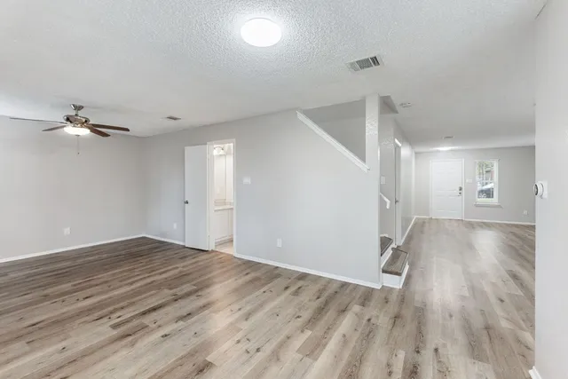 a view of a room with wooden floor and a ceiling fan