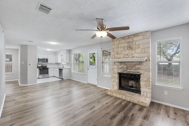 a view of a livingroom with a fireplace a ceiling fan and windows