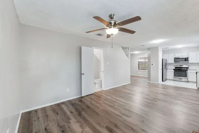 a view of a livingroom with a ceiling fan window and wooden floor