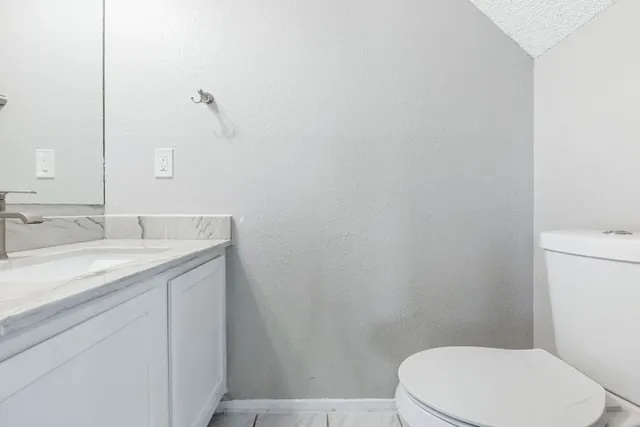 a bathroom with a granite countertop toilet and a sink