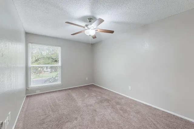 an empty room with a window and a fan