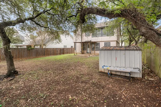 a view of a backyard with large trees and wooden fence