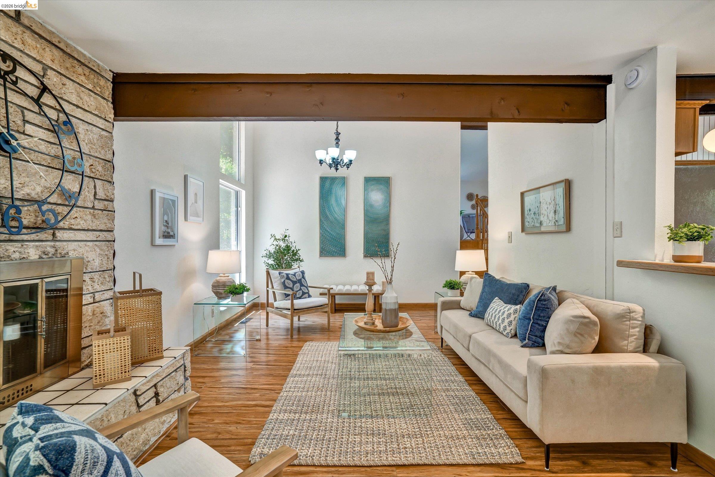 2826 Wright Avenue Pinole, CA 94564 - Photo 13 of 70 Living area featuring a stone-clad fireplace with a tiled hearth, wood-finish flooring, exposed ceiling beams, and a vaulted ceiling with high windows
