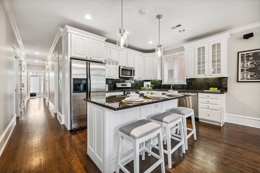 1359 North Mohawk Street, Unit 2 Chicago, IL 60610 - Photo 8 of 23 a kitchen with stainless steel appliances kitchen island granite countertop a stove a sink a refrigerator and a dining table with wooden floor