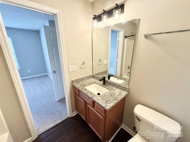 a bathroom with a granite countertop sink toilet and mirror