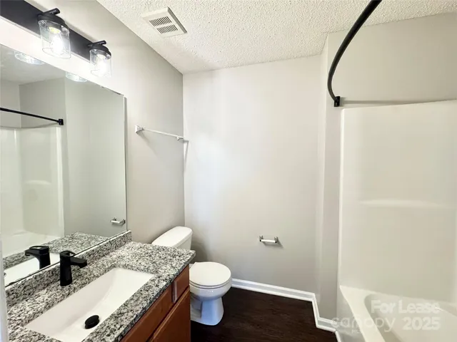 a bathroom with a granite countertop sink toilet and shower