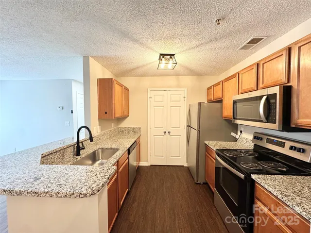 a kitchen with stainless steel appliances granite countertop a sink stove and refrigerator