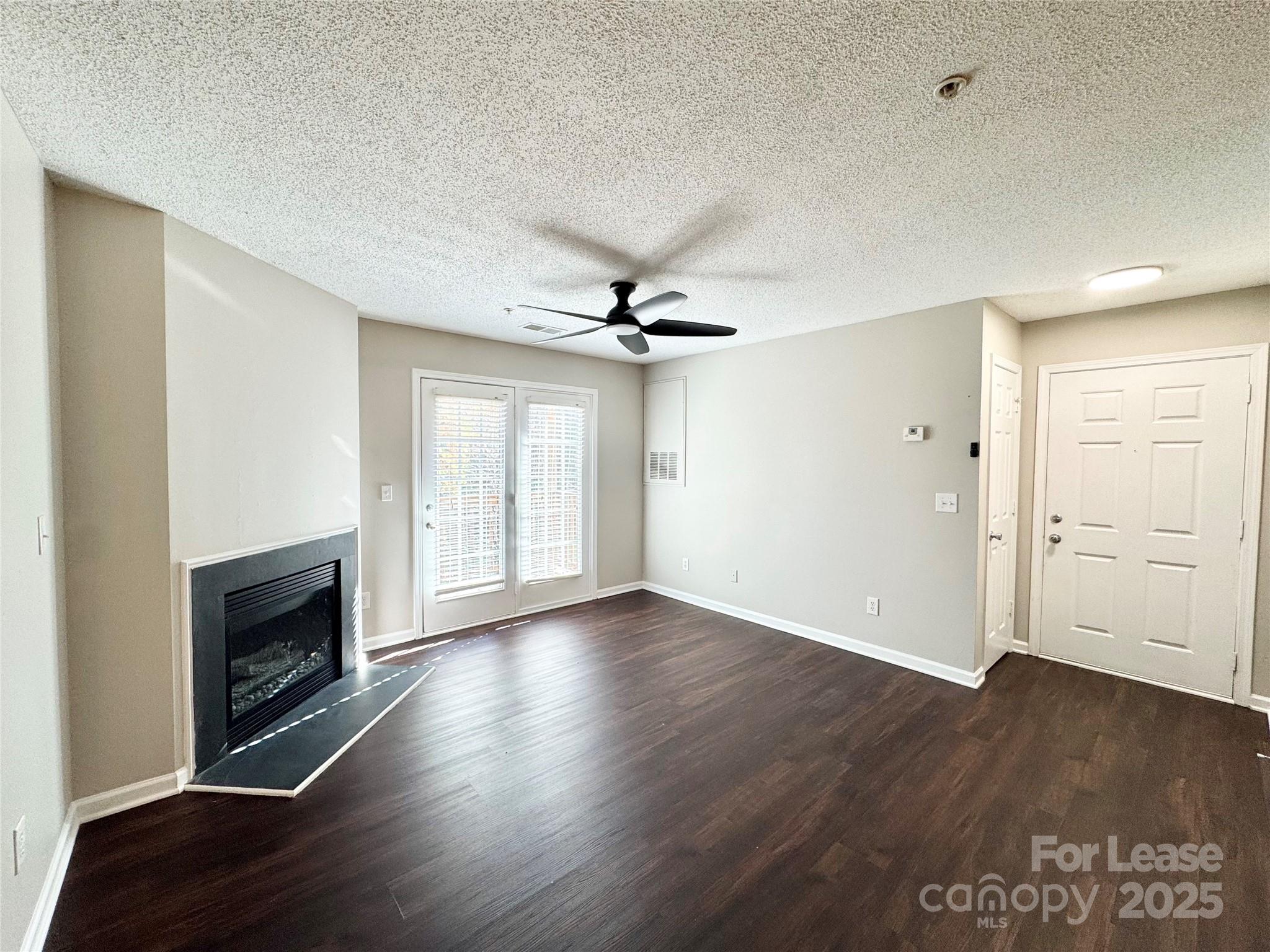 327 Flint Hill Road, Unit 203 Fort Mill, SC 29715 - Photo 5 of 18 an empty room with wooden floor fireplace and windows