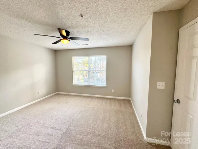 an empty room with windows and fan