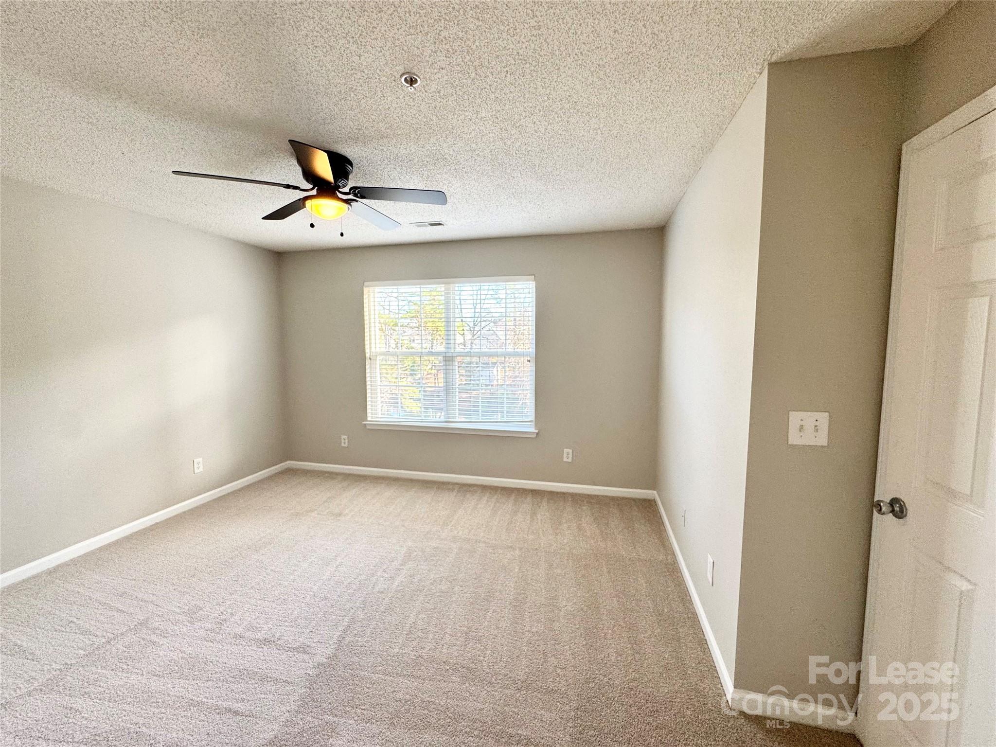 327 Flint Hill Road, Unit 203 Fort Mill, SC 29715 - Photo 9 of 18 an empty room with windows and fan