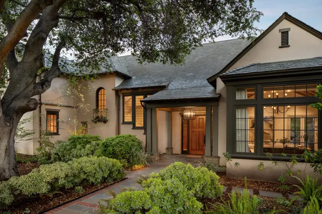 a view of a house with large windows and a tree