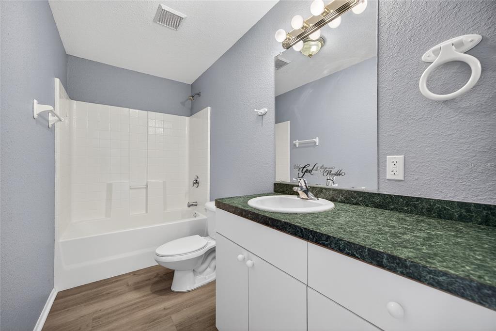 1071 Nomad Road Punta Gorda, FL 33983 - Photo 15 of 22 a bathroom with a granite countertop sink a toilet a mirror and shower