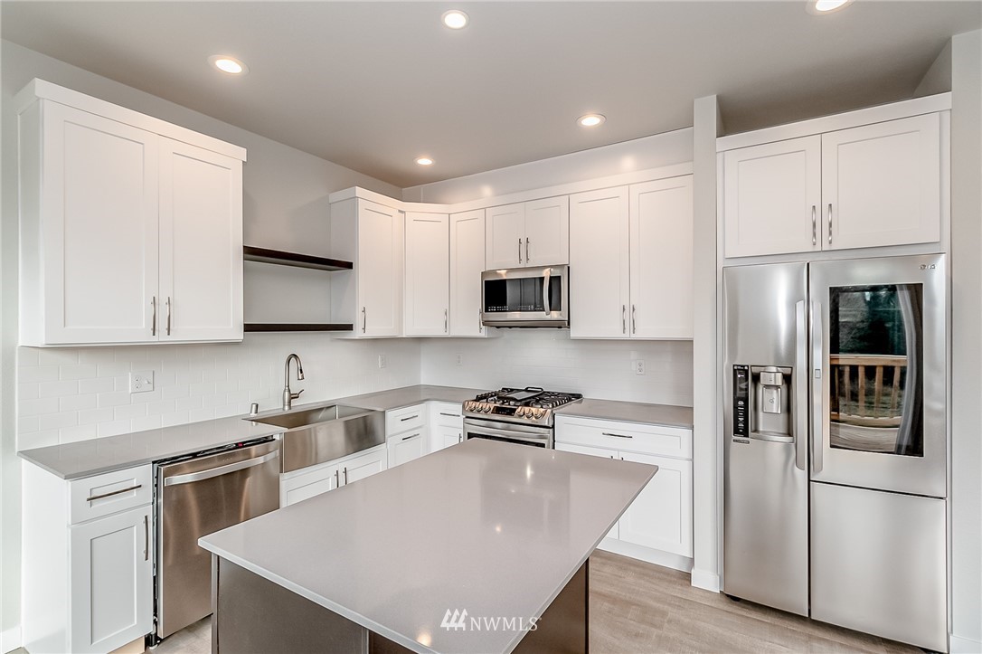 2720 Callow Road, Unit A Lake Stevens, WA 98258 - Photo 11 of 32 a kitchen with stainless steel appliances granite countertop a refrigerator a sink dishwasher a stove and white countertops with wooden floor