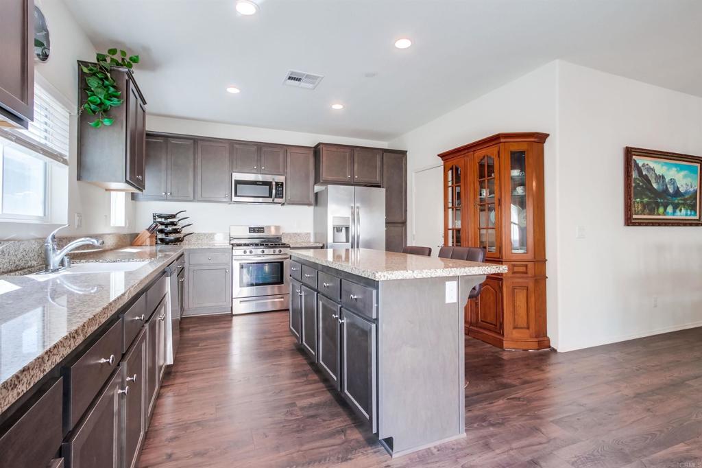 235 Spotted Saddle Way Fallbrook, CA 92028 - Photo 21 of 71 a kitchen with stainless steel appliances granite countertop a stove top oven a sink a refrigerator and a center island