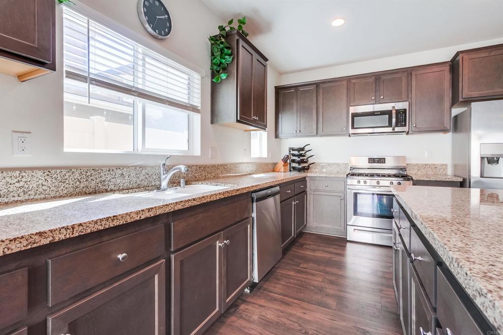 235 Spotted Saddle Way Fallbrook, CA 92028 - Photo 22 of 71 a kitchen with stainless steel appliances granite countertop a sink a stove and a wooden floors