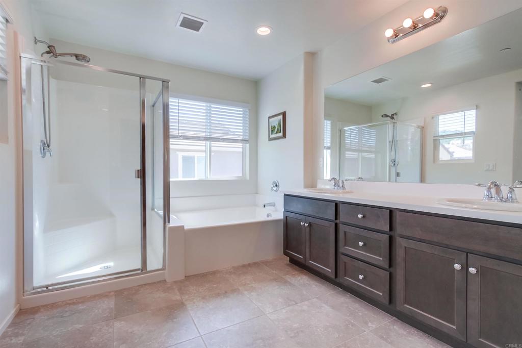 235 Spotted Saddle Way Fallbrook, CA 92028 - Photo 30 of 71 a bathroom with a tub a sink shower and mirror