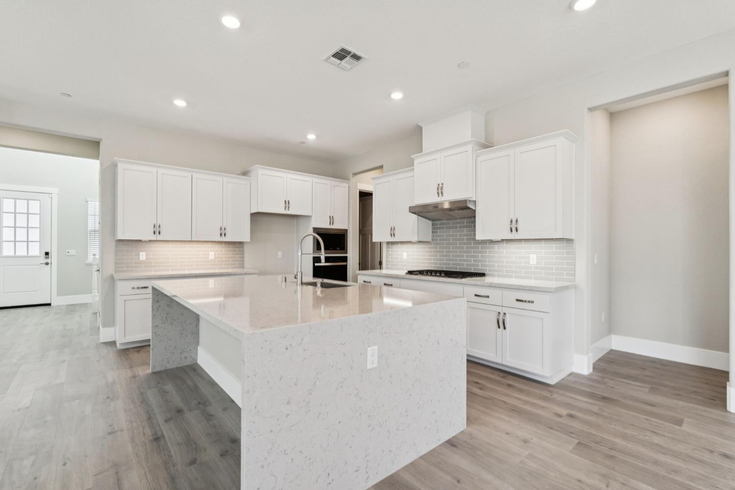 3031 Pocosol Way Rancho Cordova, CA 95742 - Photo 17 of 47 a large kitchen with stainless steel appliances granite countertop a stove a sink a refrigerator and white cabinets with wooden floor