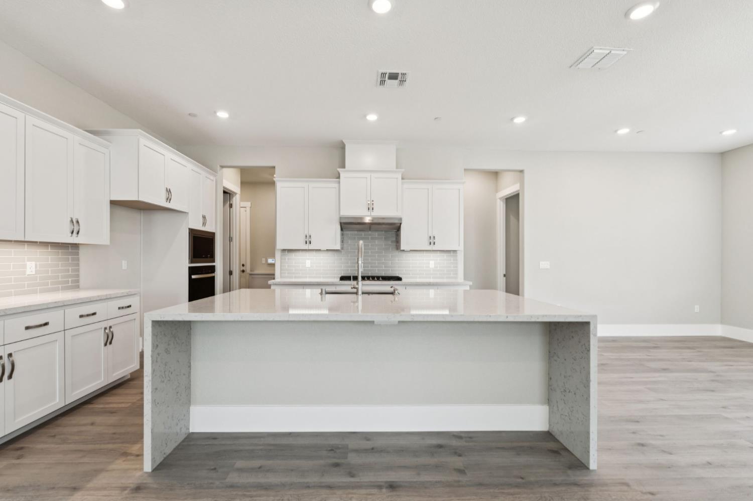 3031 Pocosol Way Rancho Cordova, CA 95742 - Photo 18 of 47 a large white kitchen with kitchen island a sink a stove and white cabinets