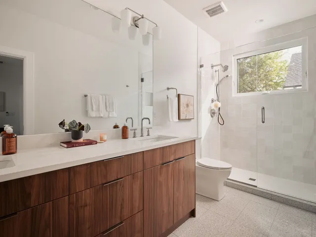 a bathroom with a double vanity sink toilet mirror and shower