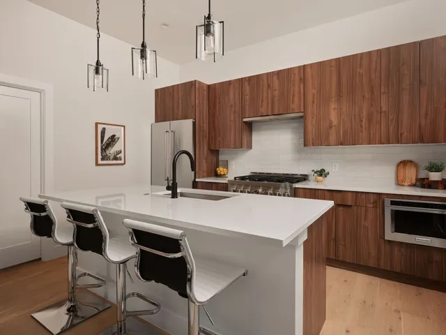 a kitchen with stainless steel appliances a stove a sink a refrigerator and wooden cabinets