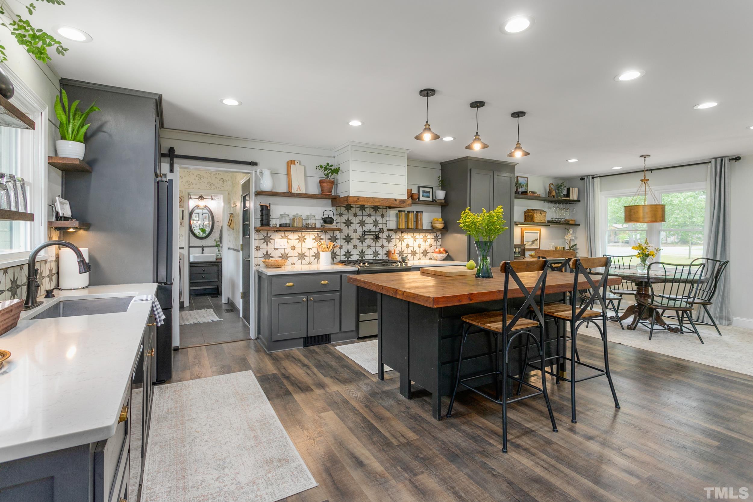 238 Alston Road Apex, NC 27523 - Photo 16 of 50 a kitchen with stainless steel appliances kitchen island granite countertop a table chairs sink and cabinets
